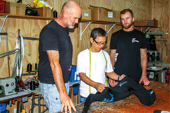 Darren and Jackson Shields discuss a new wetsuit design with staff member Sonny.