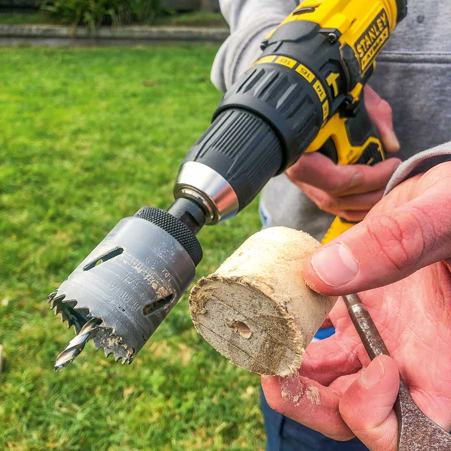 Once you have drilled entirely through the top board, you'll be left with a small cylinder wedged inside the hole saw. This can be pushed out using a screwdriver.